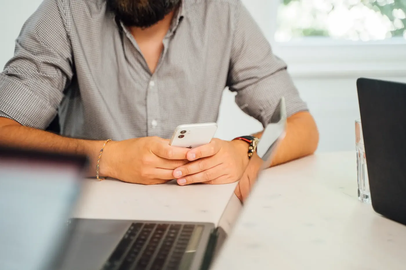 Moderator prüft einen Kommentar am Smartphone neben dem geöffneten Laptop