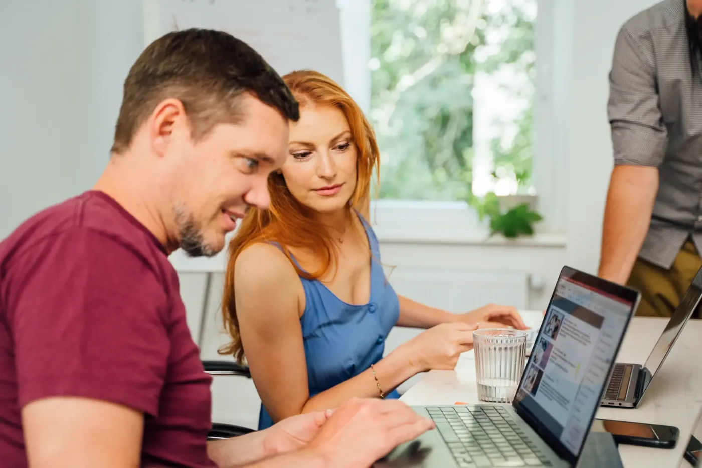 Zwei Moderatorinnen und Moderatoren sichten gemeinsam einen Social-Media-Kanal am Laptop