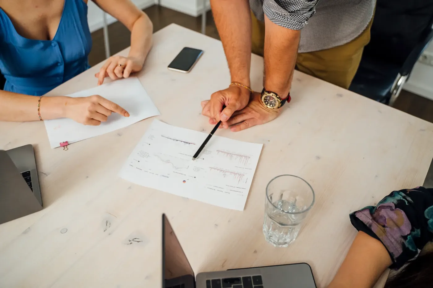 Arbeitssituation an einem Tisch mit Auswertungen, Notizen und Laptops während eines Community-Workshops